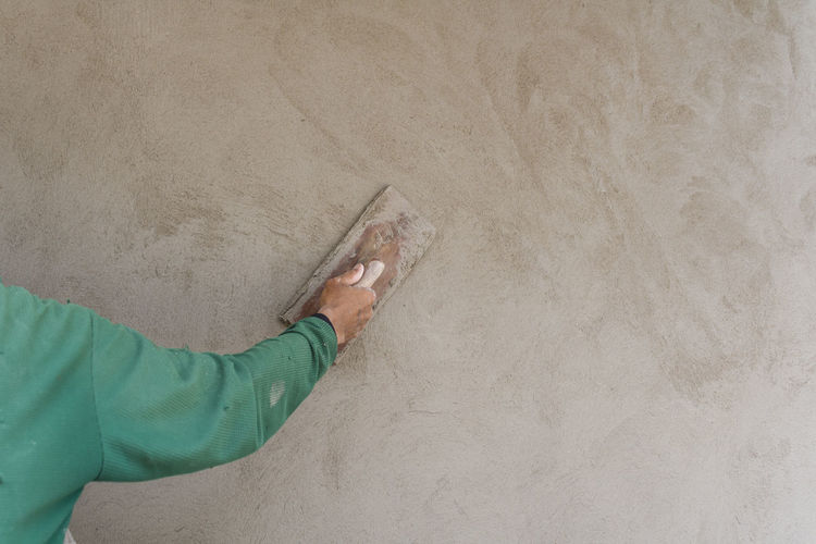 Cropped hand of worker applying cement on wall