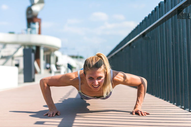 Fit young woman doing pushups outdoors