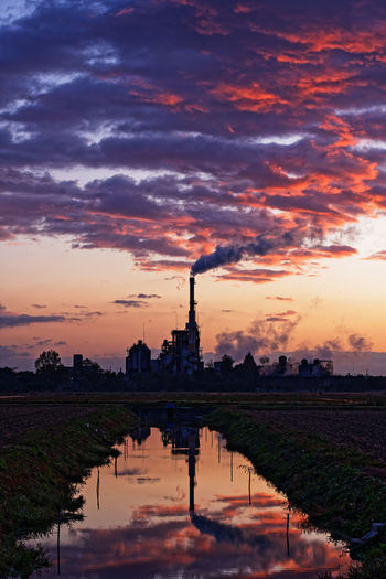 Scenic view of factory against sky during sunset
