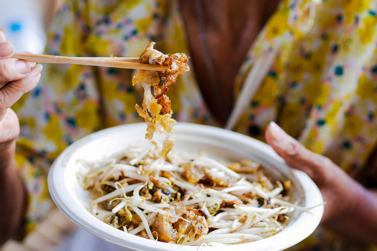 Close-up of hand holding noodles in bowl