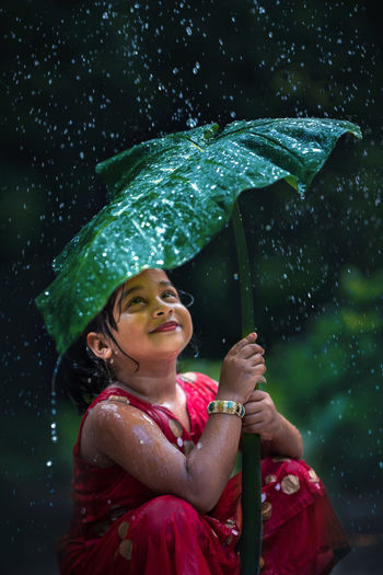 Portrait of smiling girl holding umbrella during rainy season