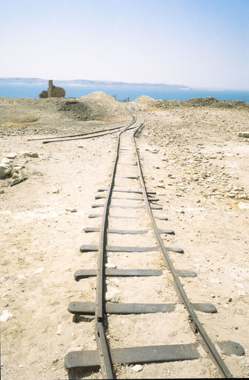 Damaged railroad track on field against clear sky