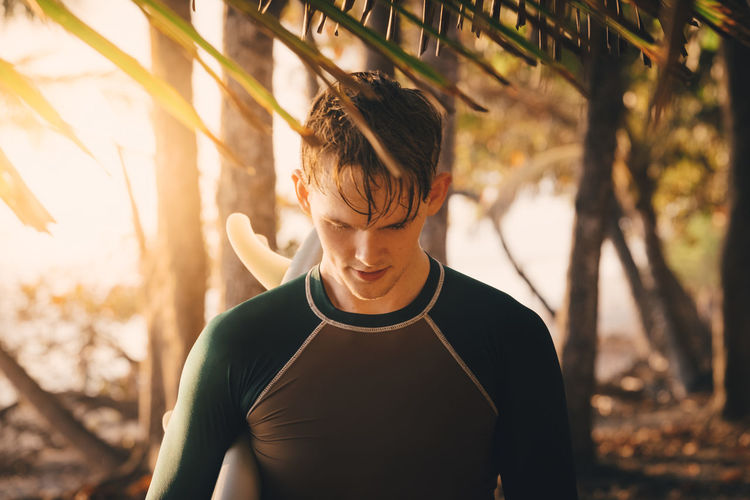 Young male surfer at beach during sunset