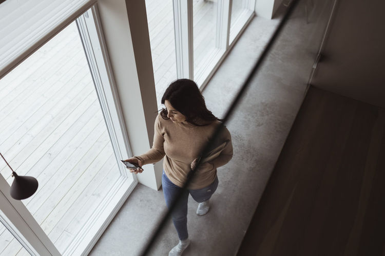 High angle view of businesswoman using smart phone while walking at home