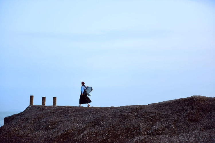 Woman walking on cliff against sky