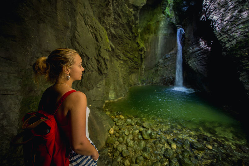 Young woman looking at waterfall in cave