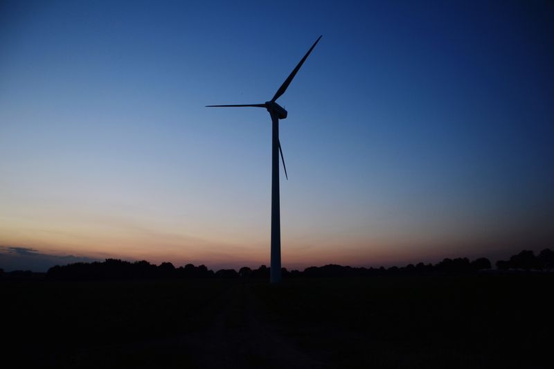Silhouette wind turbines on field against sky during sunset