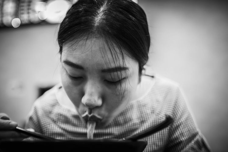 Close-up of woman eating noodles at home