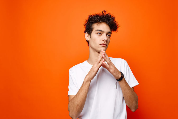 Portrait of young man against orange background