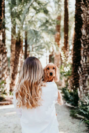 Rear view of woman with dog against trees in forest