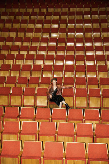 Woman sitting on chair in auditorium