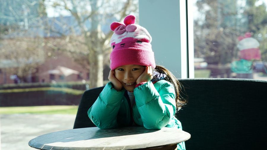 Portrait of smiling girl with hands on chin sitting at table