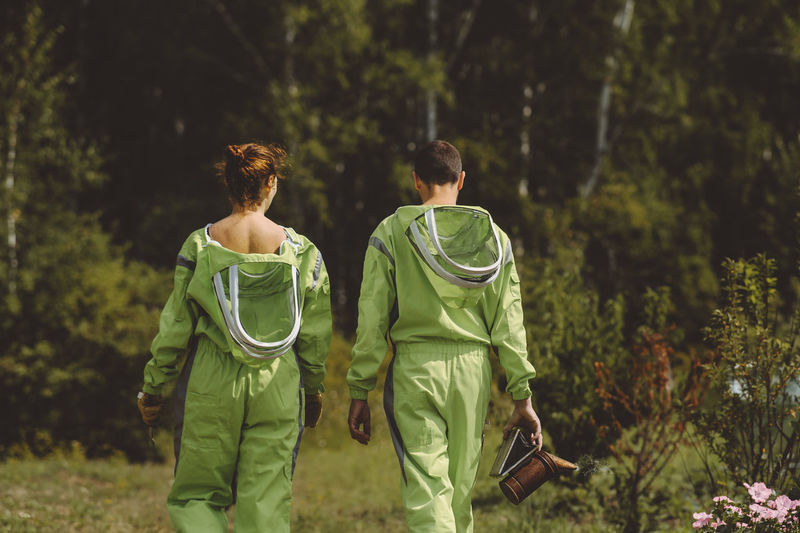 Beekeepers wearing protective suits walking together at apiary