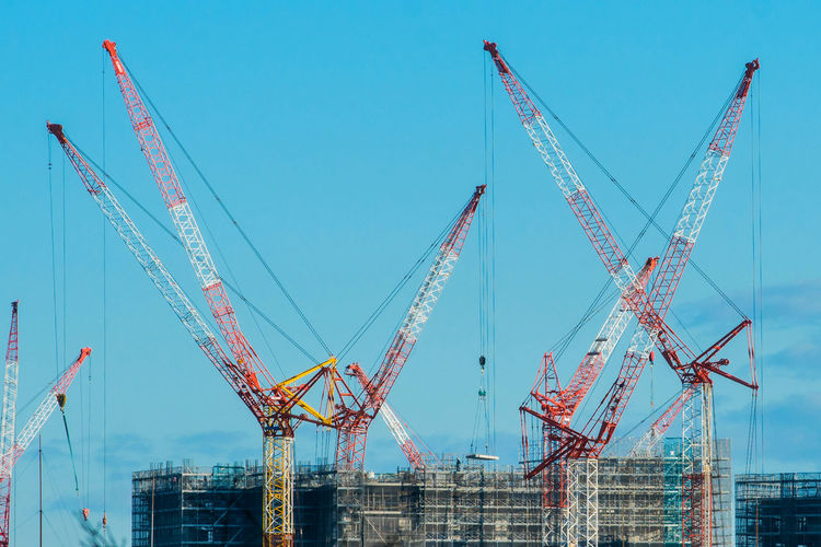 Cranes at construction site against blue sky