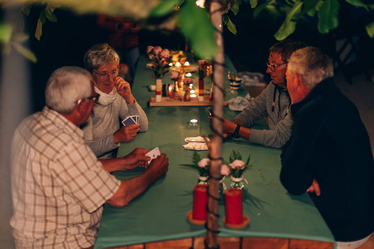 Seniors friends playing cards on late summer night - elderly people lifestyle friendship