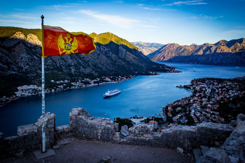Montenegrin flag waving against river and mountains