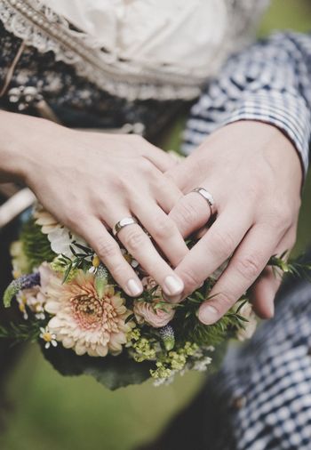 Midsection of couple with bouquet outdoors