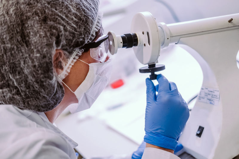 Side view of woman looking in microscope while working in laboratory.