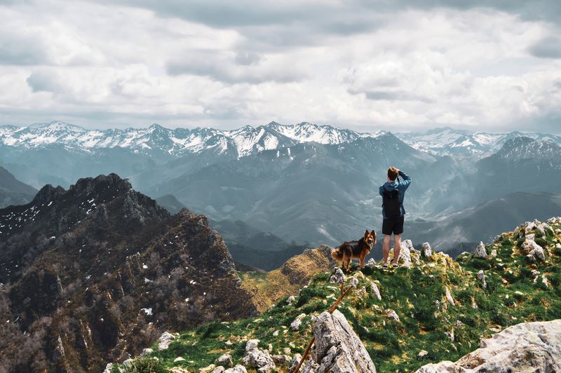 Rear view of man looking at mountains against sky