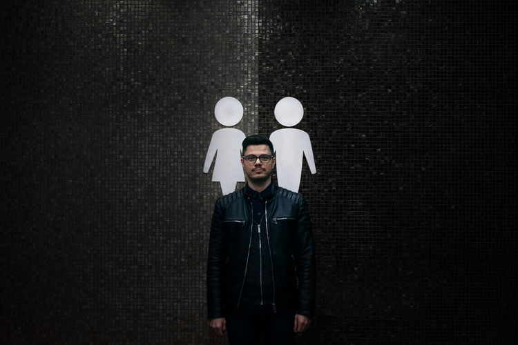 Portrait of man standing against symbols on wall