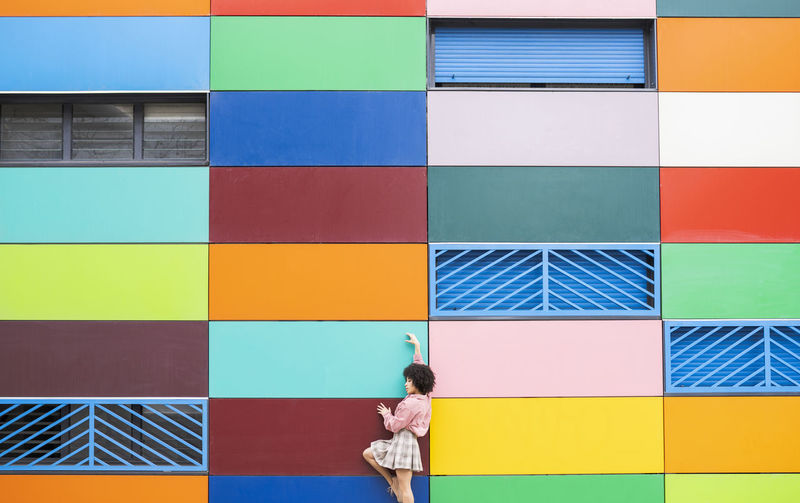 Young dancer standing with hand raised by colorful building