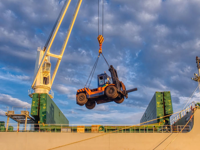 The ship's crane is moving forklift and special tool to operate cargo on board.