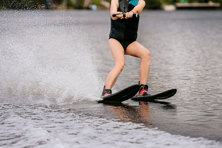 Low section of woman wakeboarding in lake
