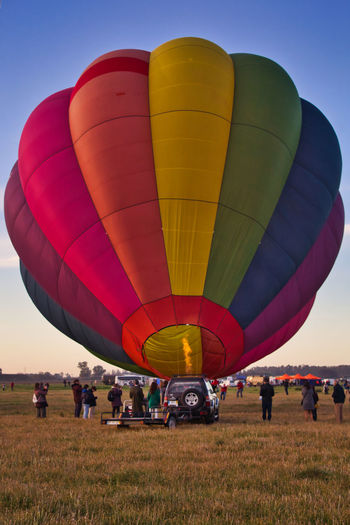 View of hot air balloons on field against sky