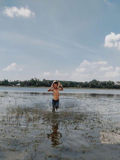 Portrait of man standing in water against sky