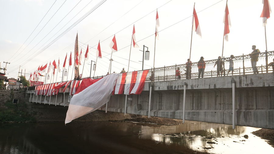 Low angle view of flags hanging on bridge over river
