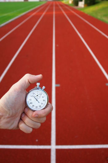 Close-up of hand holding stopwatch at running track