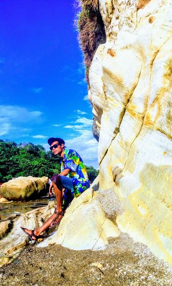 Man standing on rock against sky