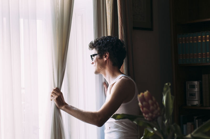 Young man standing by window at home