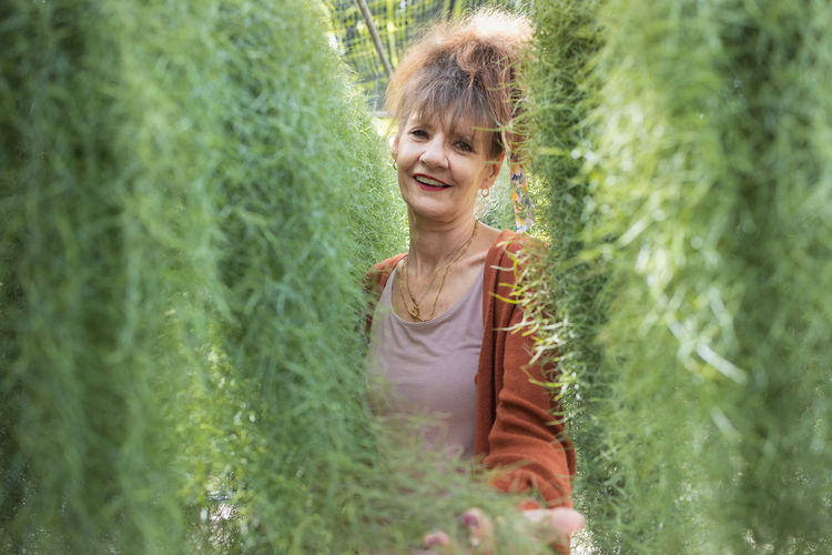 Portrait of young woman standing amidst plants