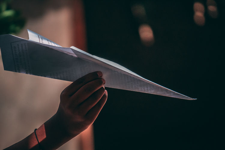 Cropped hand holding paper plane 