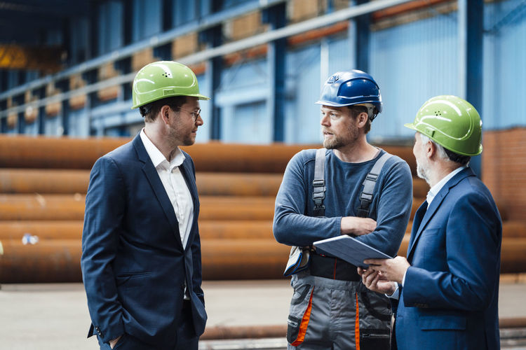 Male warehouse worker discussing with business professionals at warehouse
