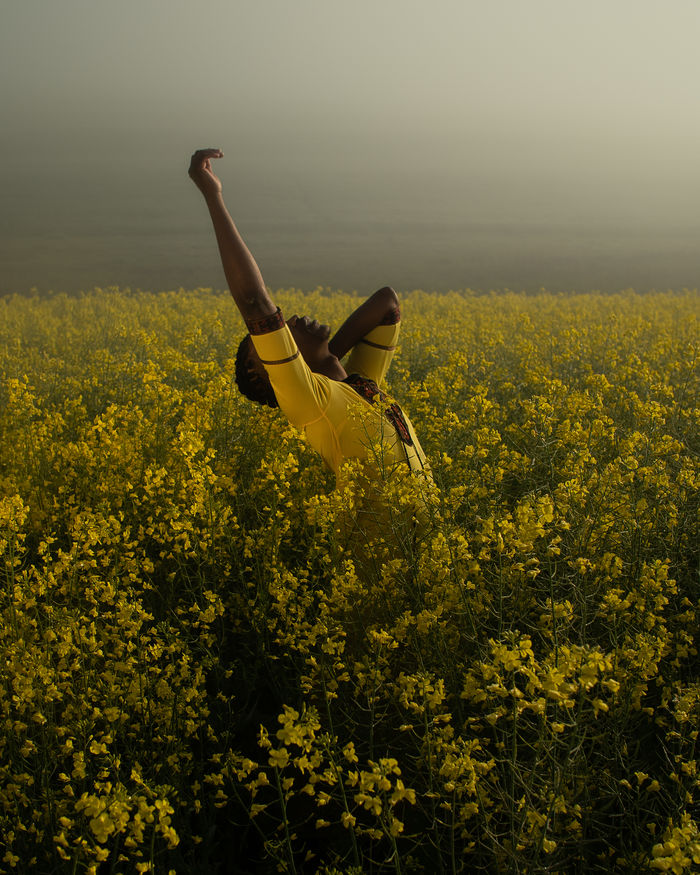 Young man standing amidst yellow flowers on oilseed rape landscape