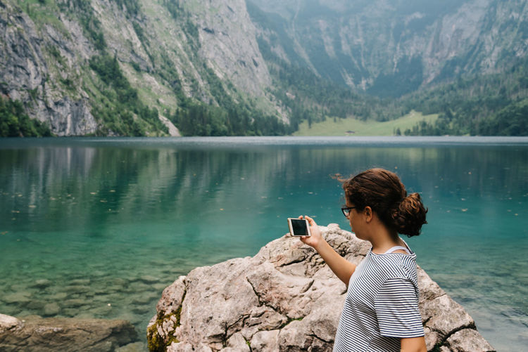 Woman photographing through mobile phone at lake