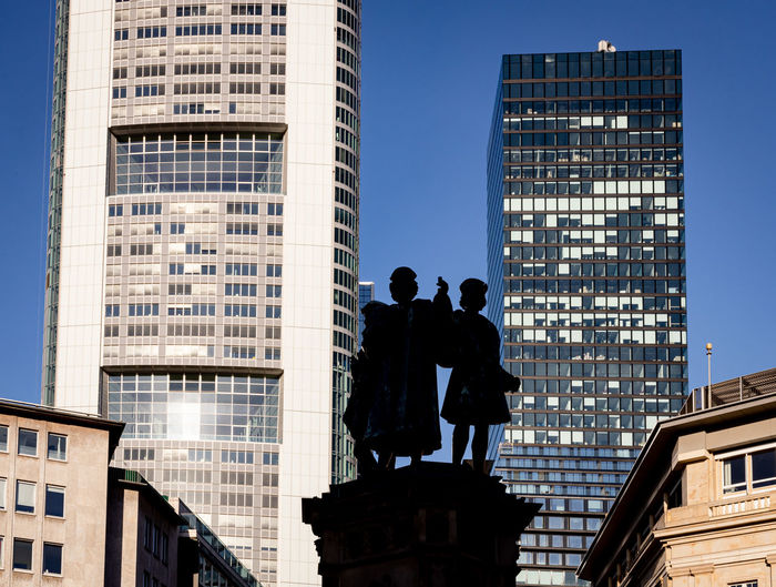 Low angle view of statues and buildings against sky in city