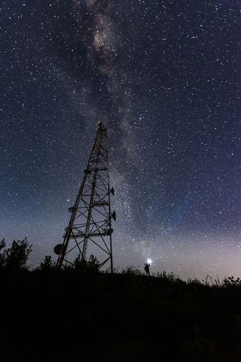 Low angle view of silhouette tower against milky way sky at night