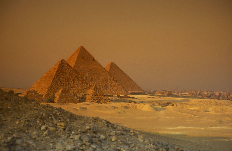 Ancient stone pyramids on desert landscape against sky