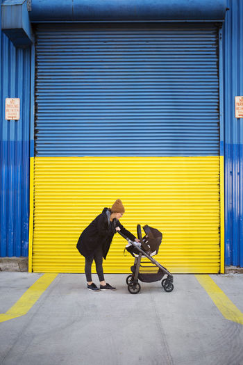 Side view of woman with baby carriage on street