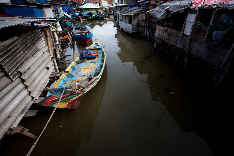 Boat moored at canal amidst houses
