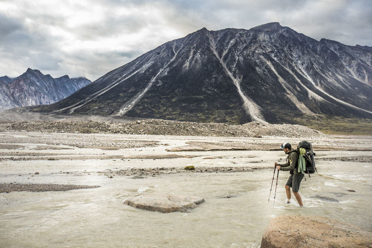 Hiker faces adversity, crossing a braided river channel.