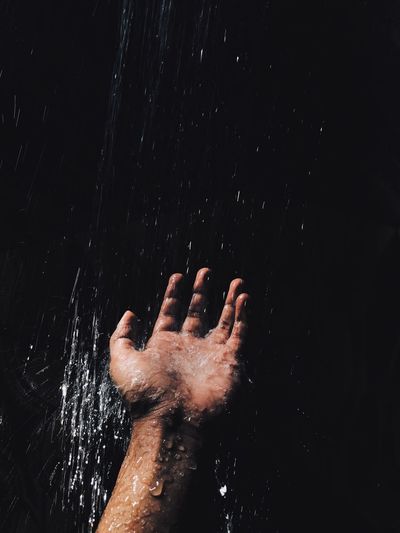 Water splashing on hand against black background
