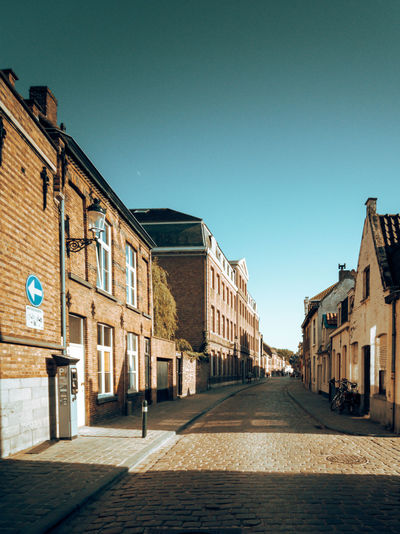 Cobbled street amidst medieval houses against clear blue sky