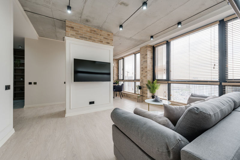 Interior in a modern style and a view of the tv and part of the kitchen near the large windows 