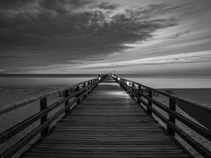 Pier over sea against sky during sunset