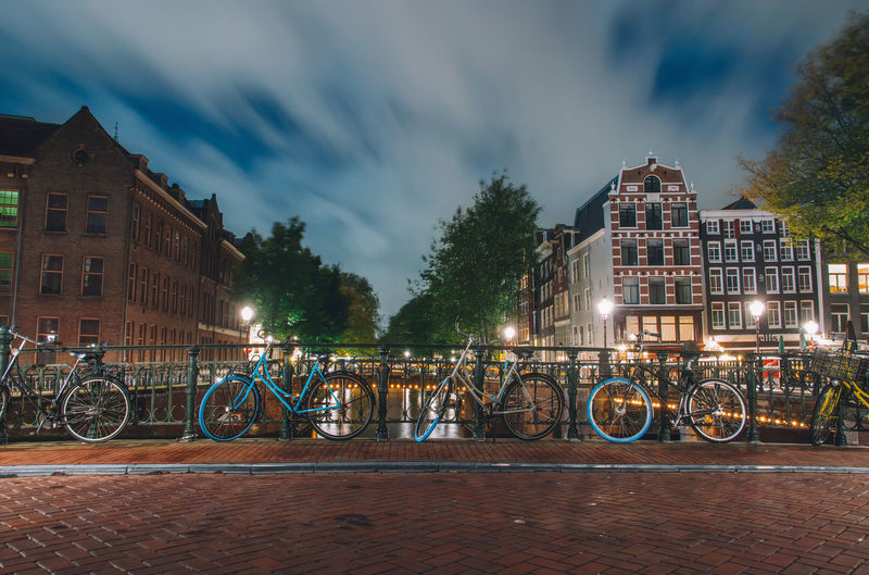 Bicycle parked by building against sky at night
