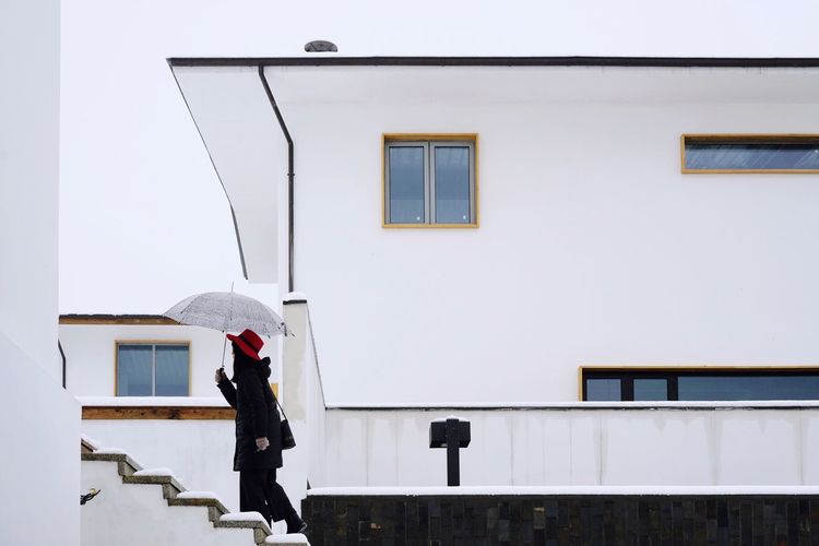 Side view of mid adult woman with umbrella moving up on steps during winter